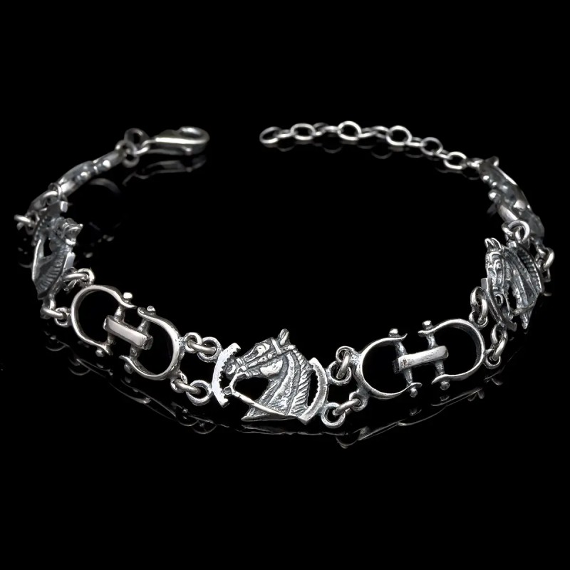 Pulsera abierta y envejecida de Caballos y Bocados sobre fondo negro.